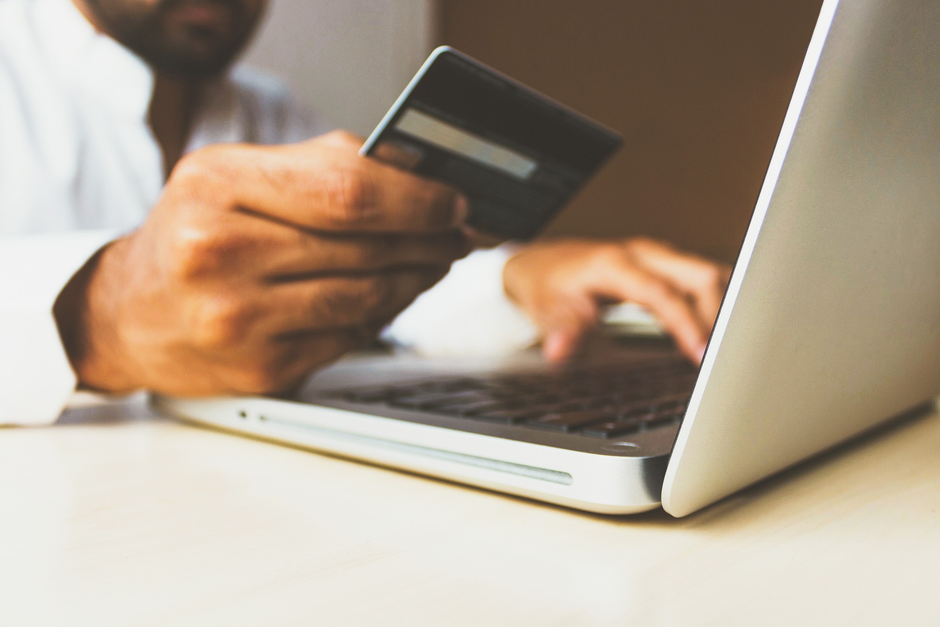 Person on laptop computer holding plastic credit or debit card