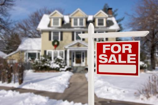 Snow covered home with for sale sign